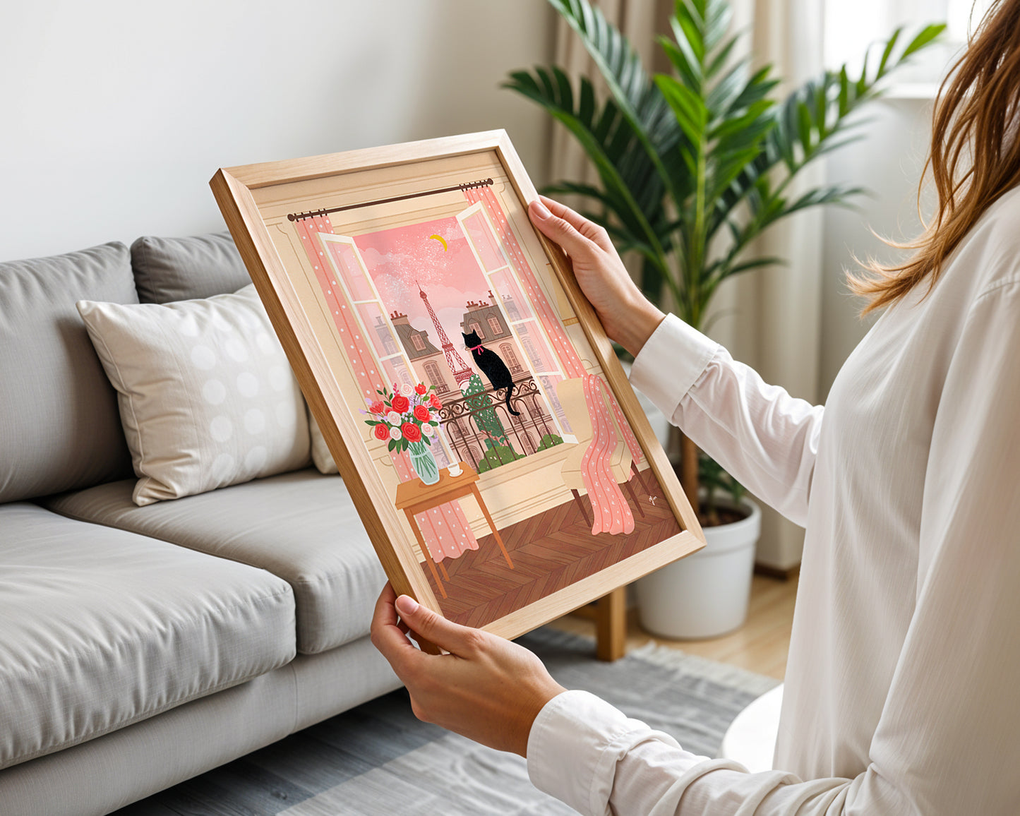 An illustration of a black cat with a pink ribbon sitting on a balcony, looking out at the Eiffel Tower through open windows, with pink curtains, flowers, and a cozy interior