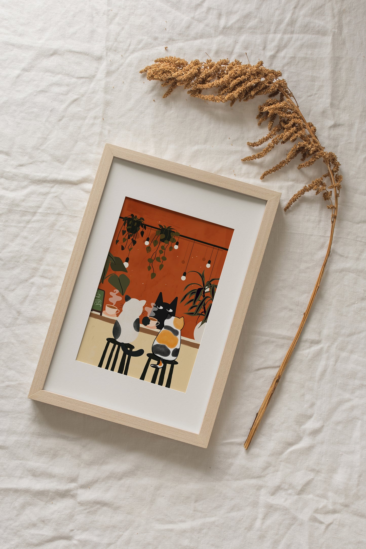 Three cartoon-style cats sit at a café counter sipping coffee. A black cat faces forward with a cup in hand, while a white and black cat and a calico cat sit on bar stools from behind. The warm orange background is decorated with hanging string lights and potted plants, creating a cozy café atmosphere.
