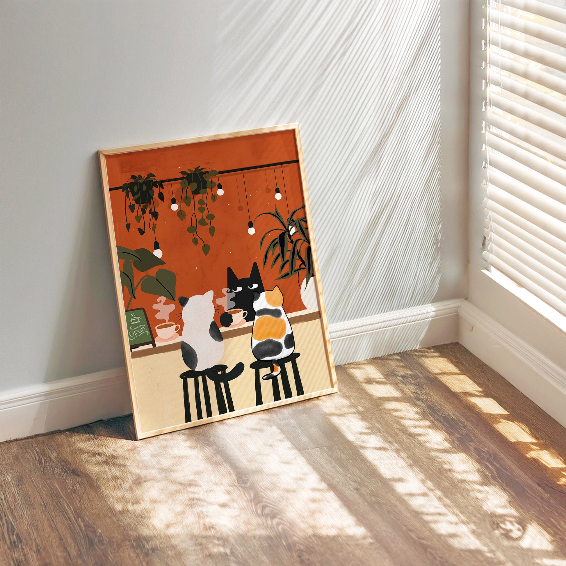 Three cartoon-style cats sit at a café counter sipping coffee. A black cat faces forward with a cup in hand, while a white and black cat and a calico cat sit on bar stools from behind. The warm orange background is decorated with hanging string lights and potted plants, creating a cozy café atmosphere.