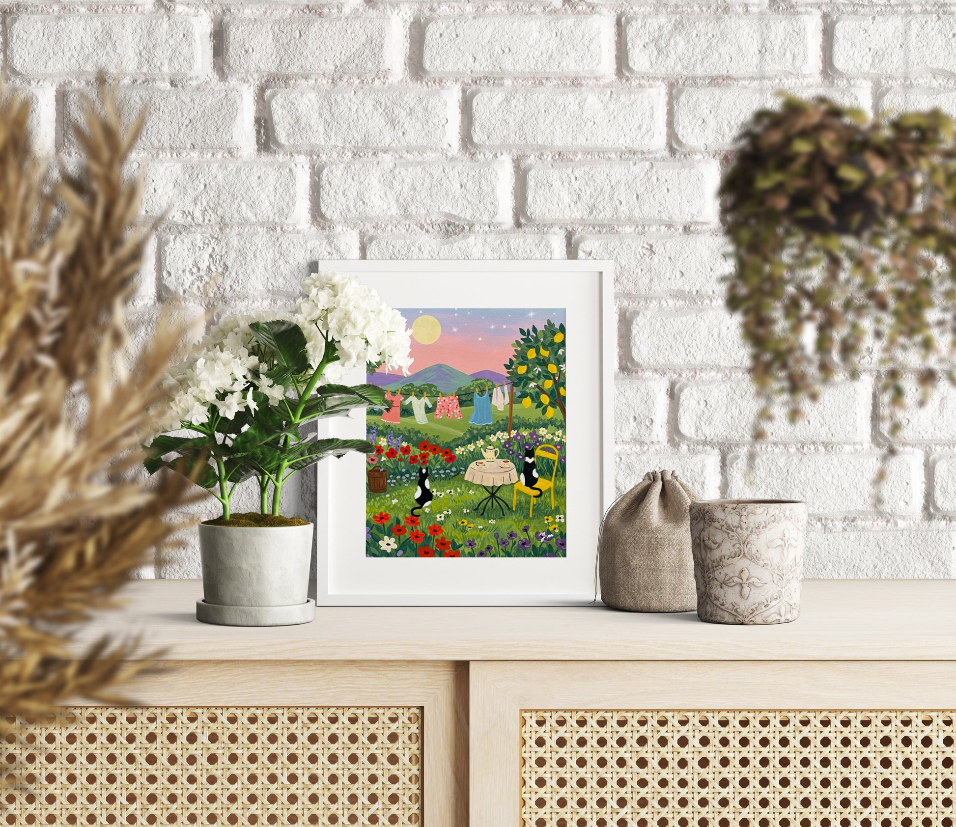 Two cats having tea at sunset with a laundry line in the background and a whimsical landscape scene perfect for cozy home wall decor